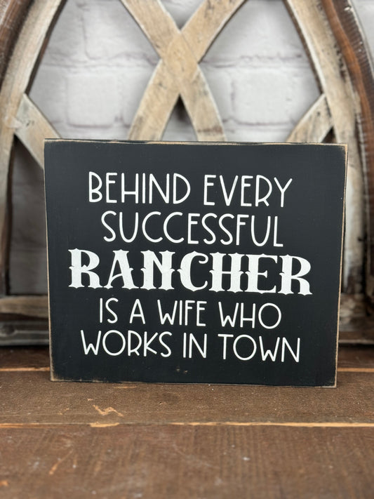 BEHIND EVERY SUCCESSFUL FARMER/RANCHER IS A WIFE WHO WORKS IN TOWN- WOOD SIGN